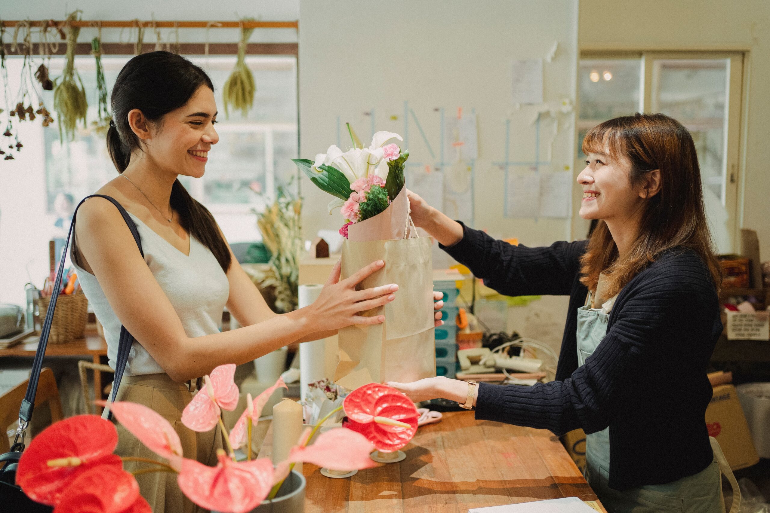 Retail business owner assisting a customer while holding a bouquet, illustrating business loans retail financing.